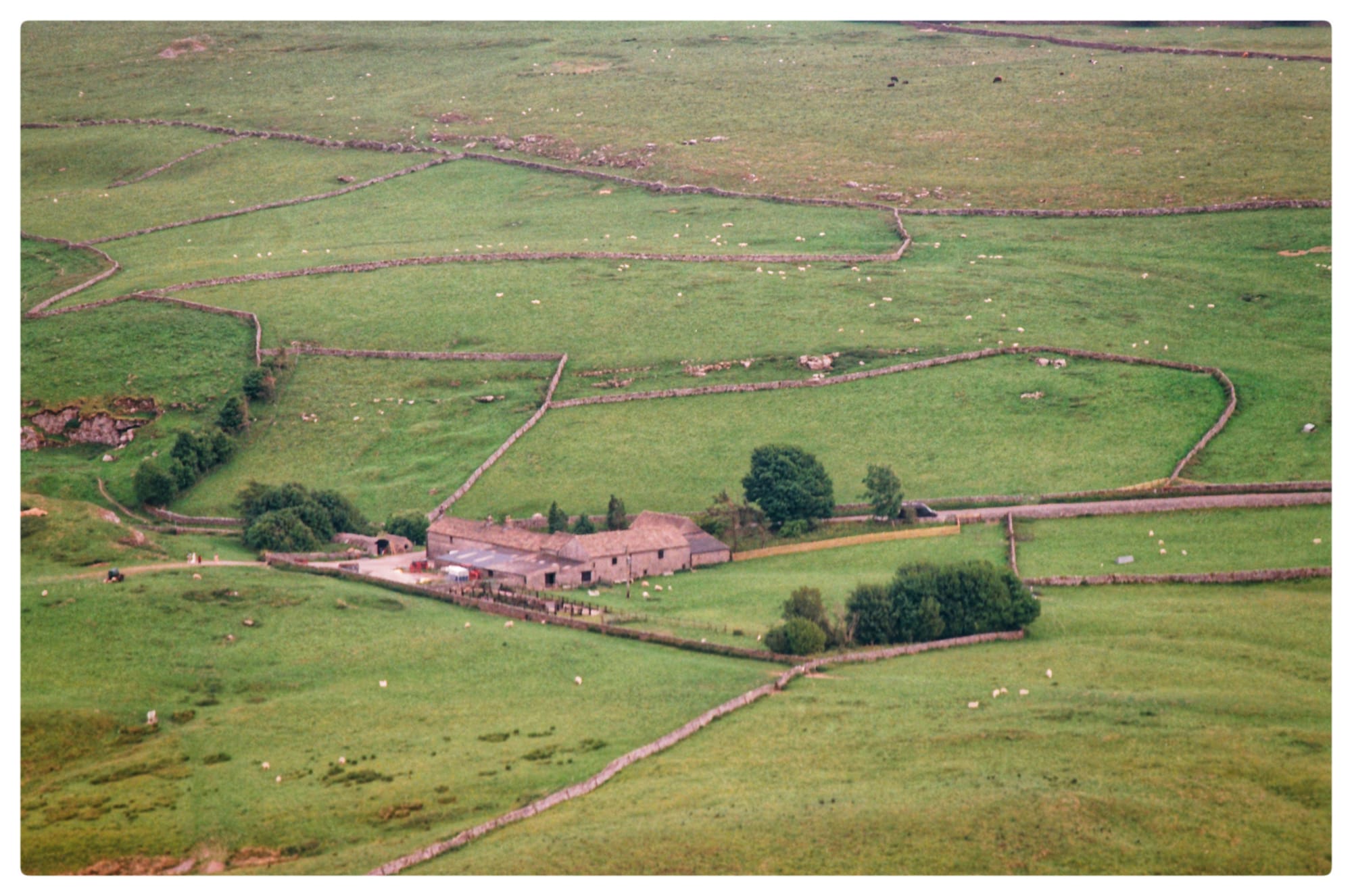 Film picture of a farmhouse taken from the peak of Mam Tor in the Peak District