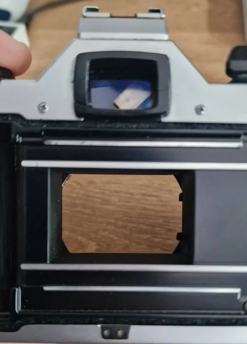 Back of the Pentax MG where it shows the viewfinder having a piece of metal in it and the shutter not closing